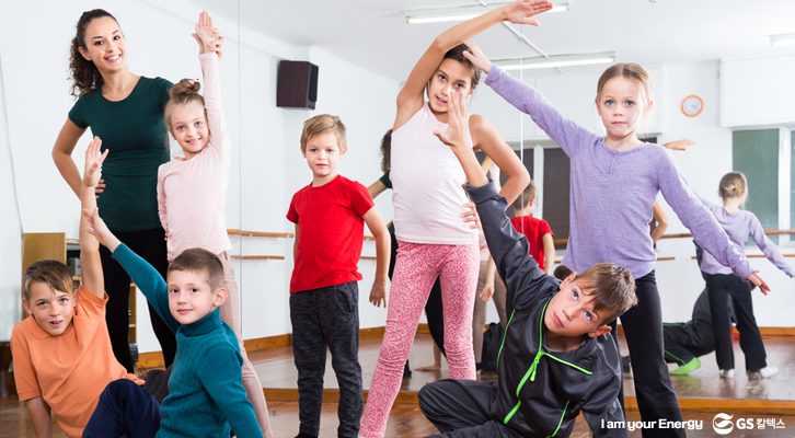 무용 연습실에서 아이들과 선생님이 포즈를 취하는 모습