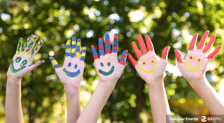 아이들이 손에 물감으로 웃는 얼굴을 그린 모습