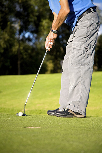 male golfer about to shot in a putting green near the hole 퍼팅